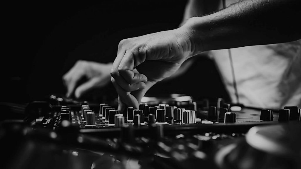 A person working on a DJ set and making music.