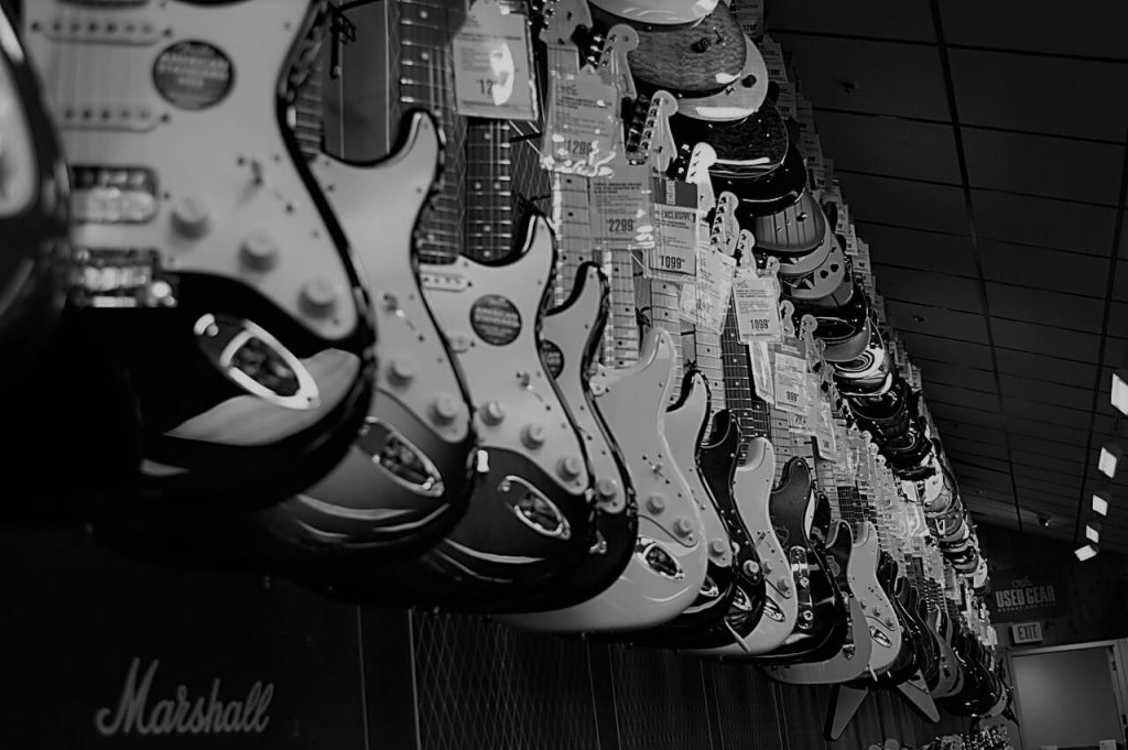 An enticing photo of a guitar store featuring two rows of electric guitars on display.
